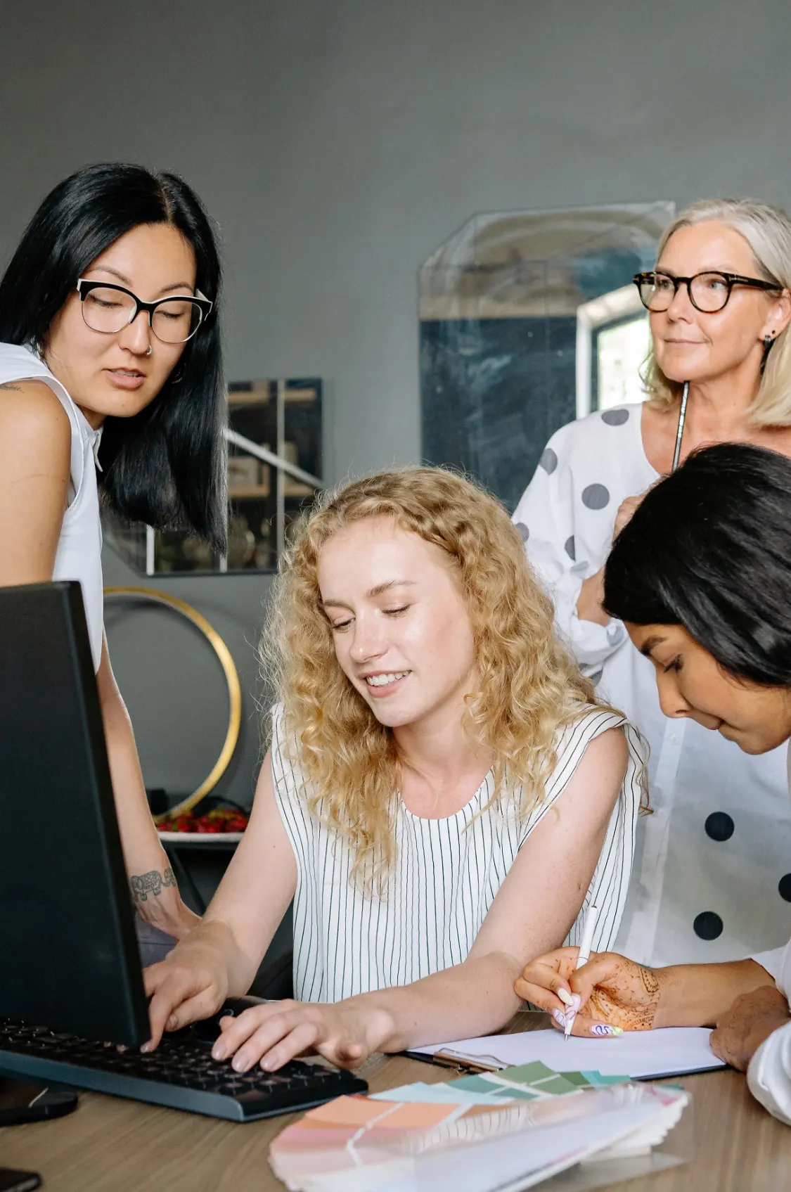 Equipe reunida em volta do computador conversando sobre um projeto
